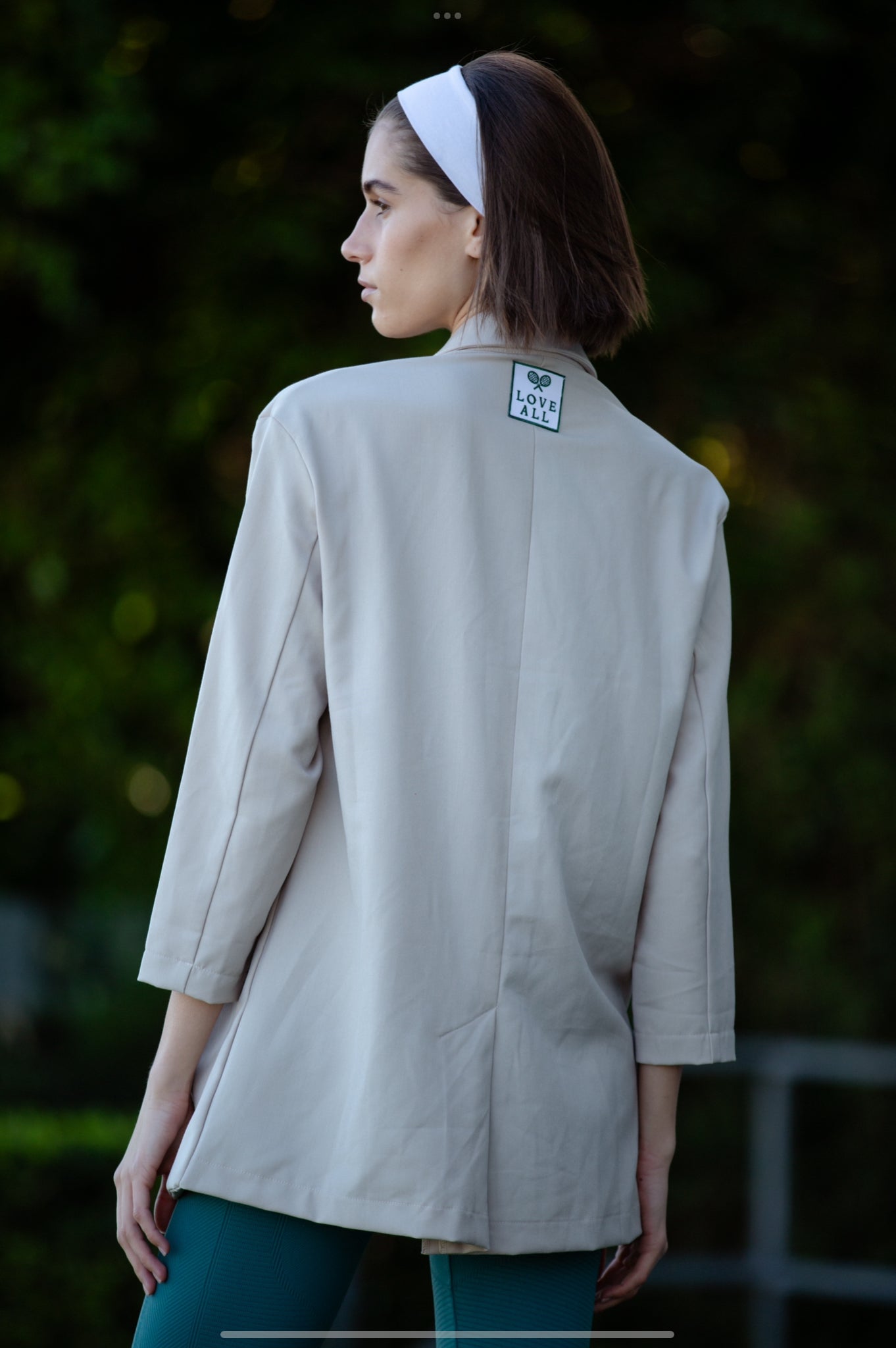 A woman wearing a beige oversized blazer, back view