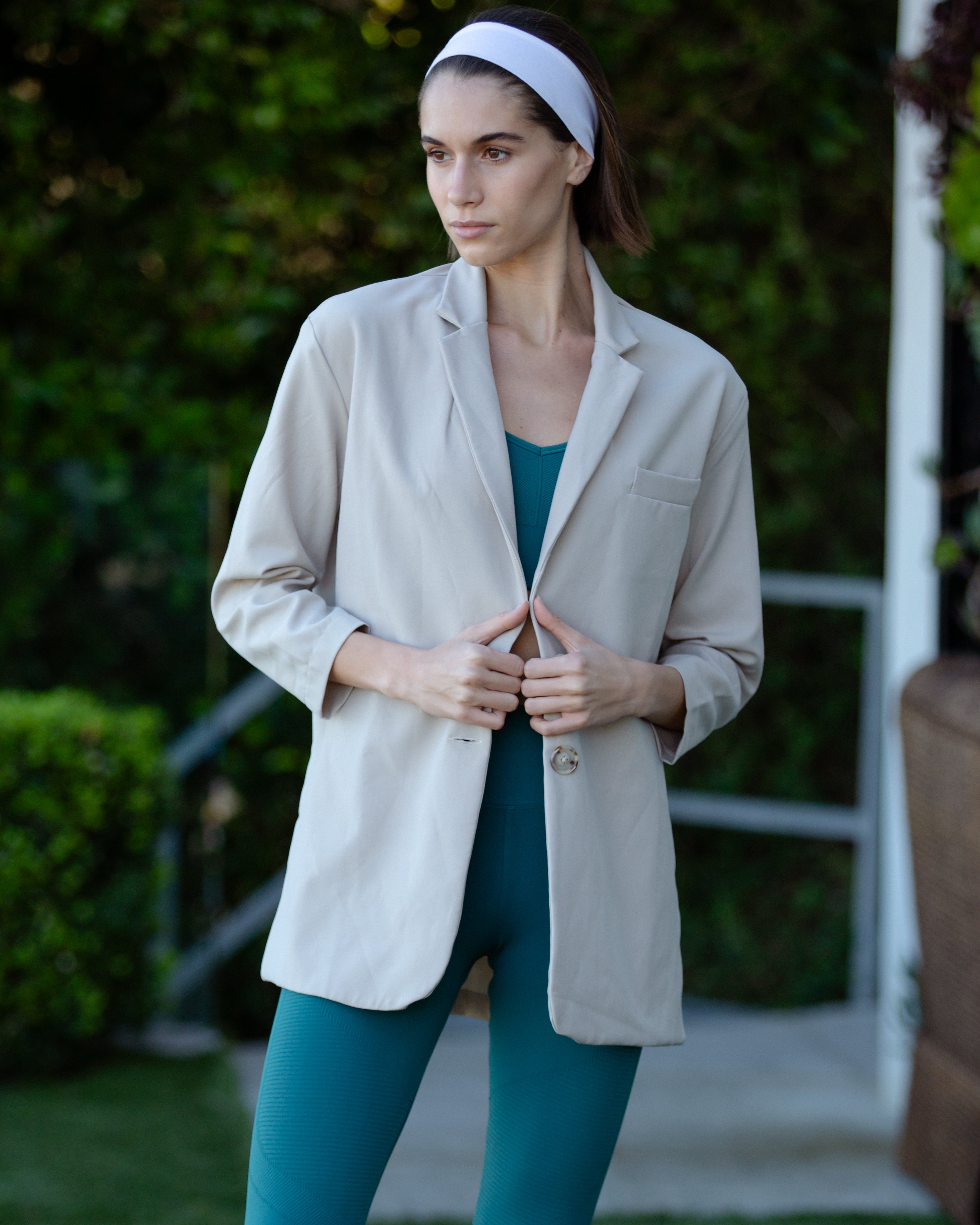 A woman wearing a beige oversized blazer posing outdoors.