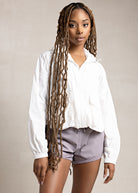 A person wearing lilac-colored sporty shorts with a drawstring waist, paired with a white top. 